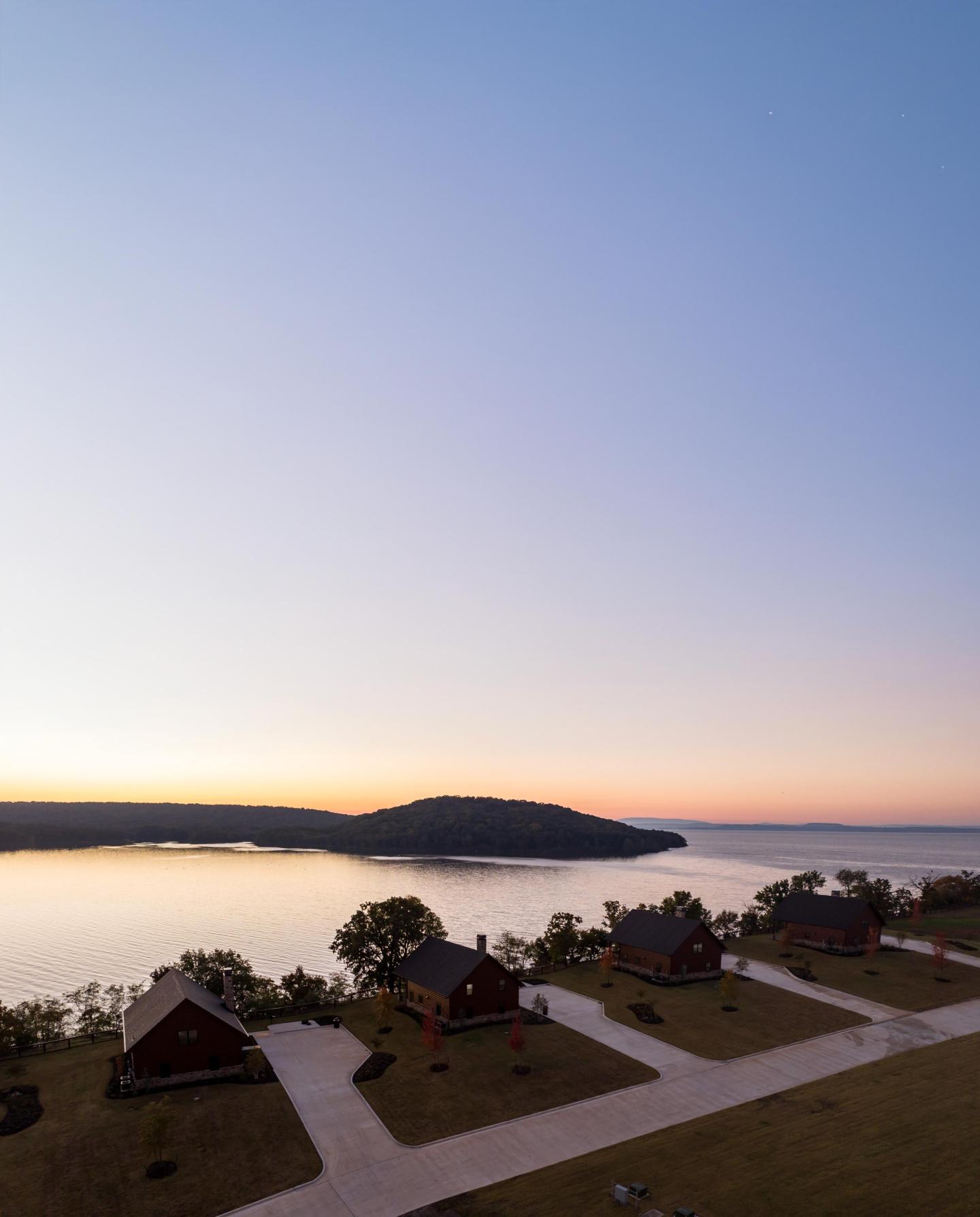 Cabins by a lake at sunset with a clear, colorful sky.