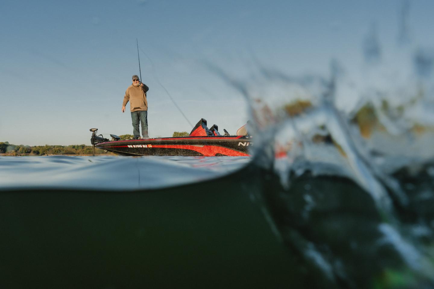 Fishing from a red boat, captured underwater with a splash.