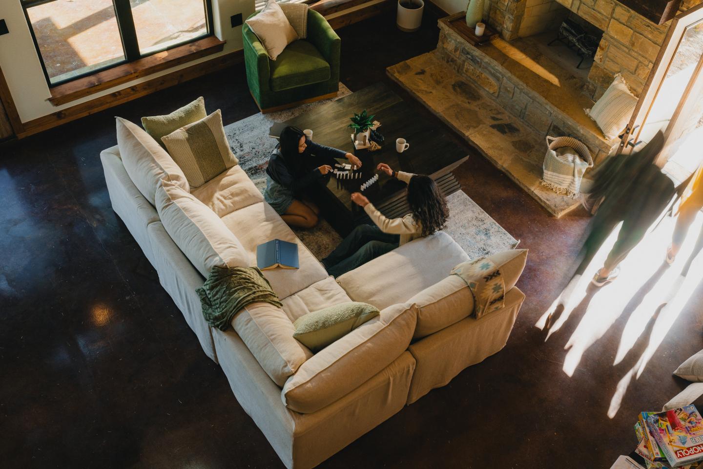 Cozy living room with people relaxing on a sectional sofa near a fireplace.