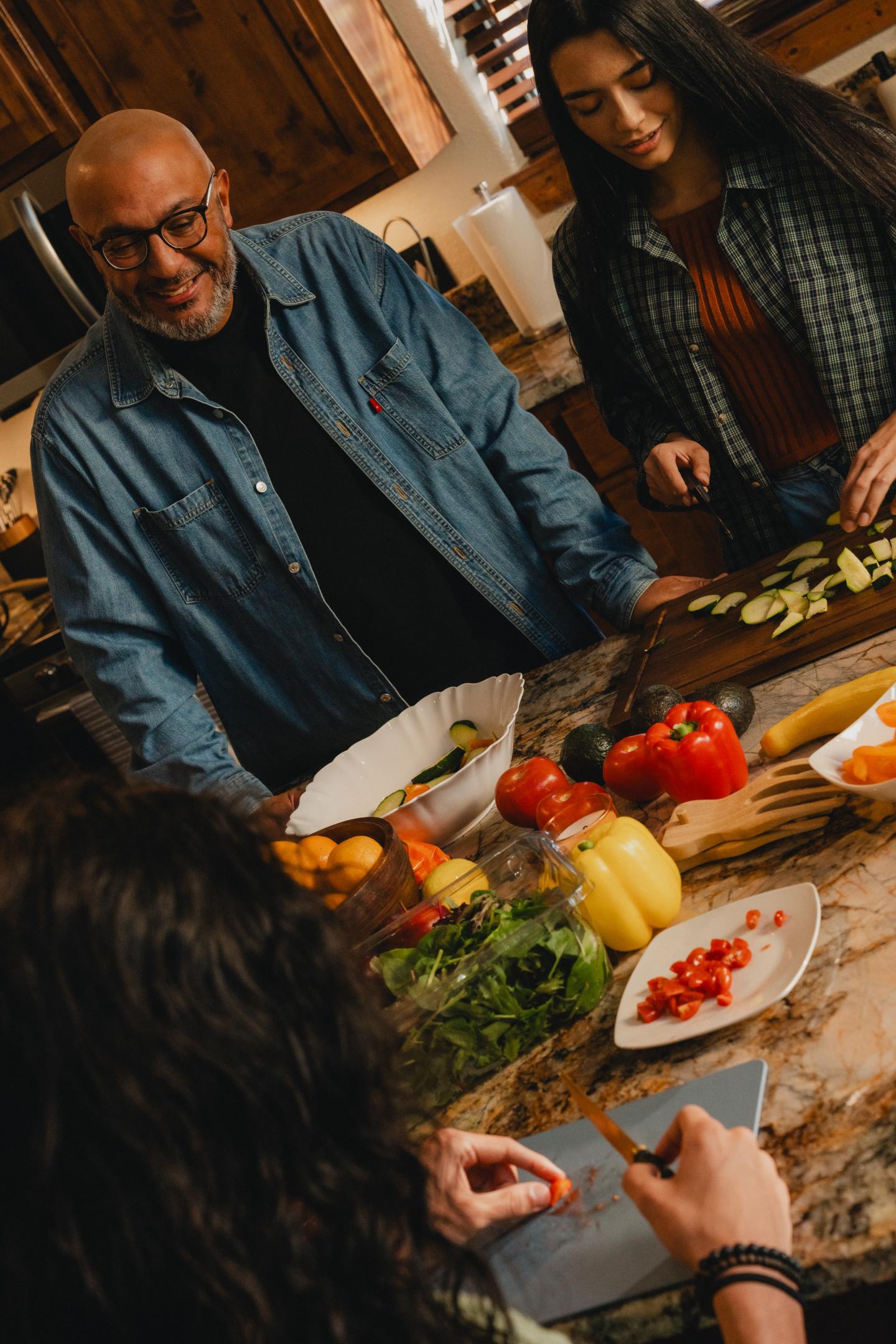 Family cooking together in a kitchen, chopping vegetables on a counter.