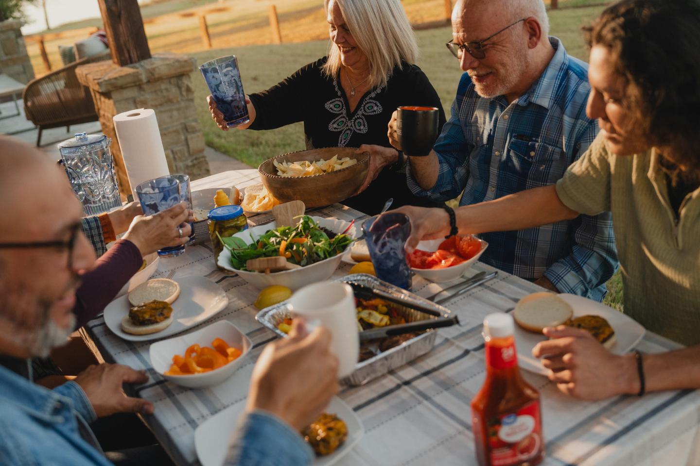 Friends enjoying a meal outdoors, clinking glasses in a cheerful setting.