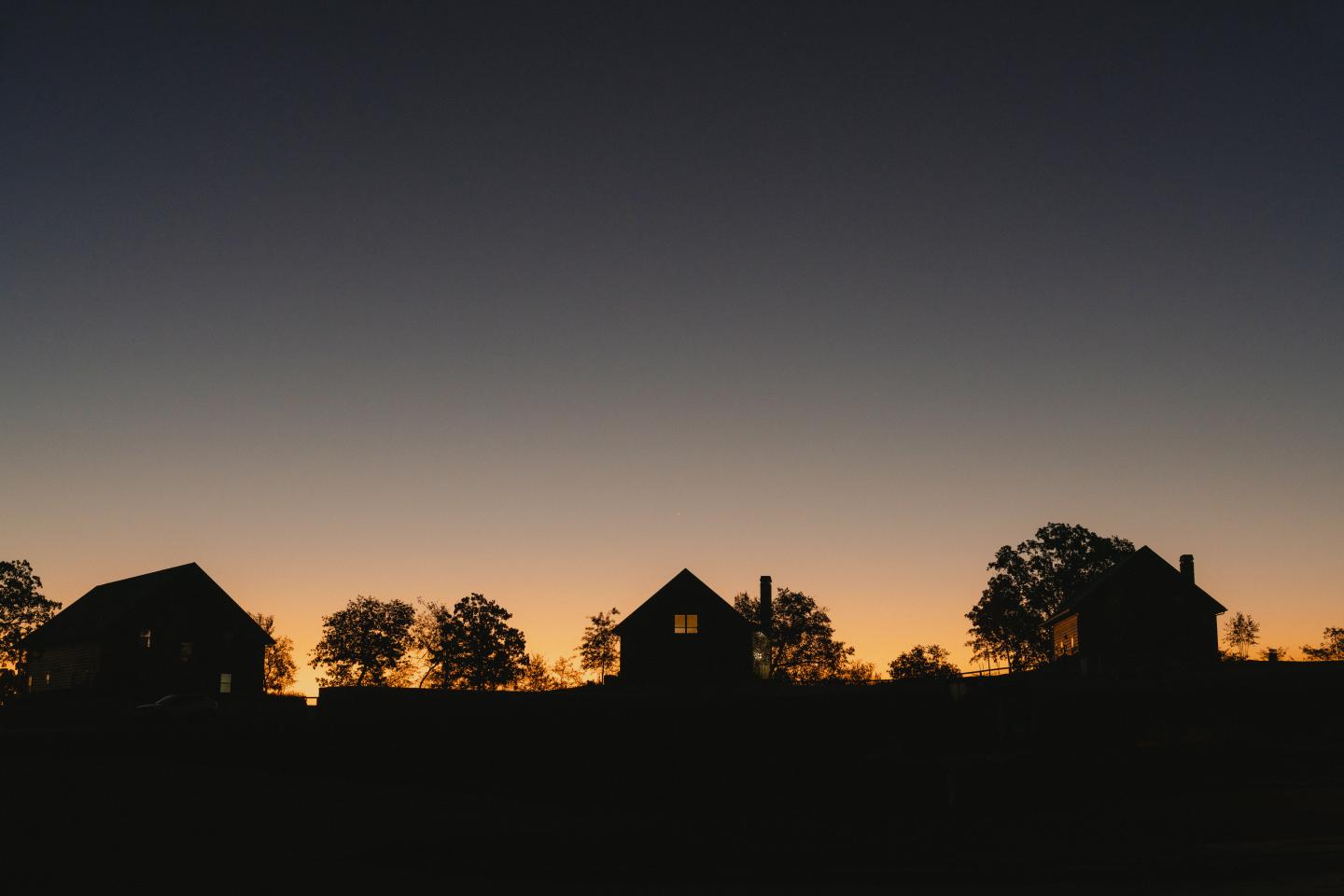 Silhouette of houses and trees against a sunset sky.