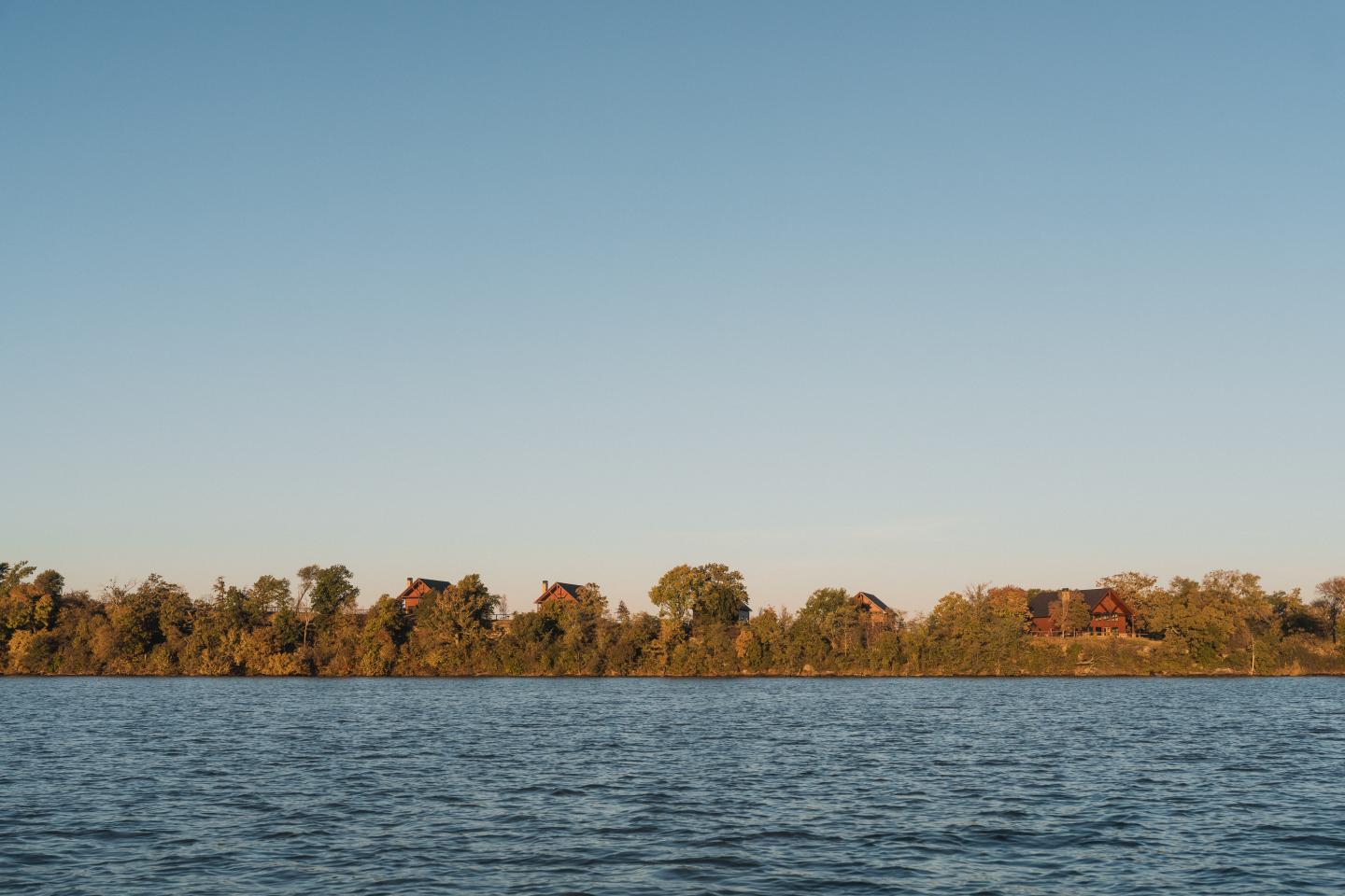 Calm lake with a tree-lined shore under a clear blue sky.