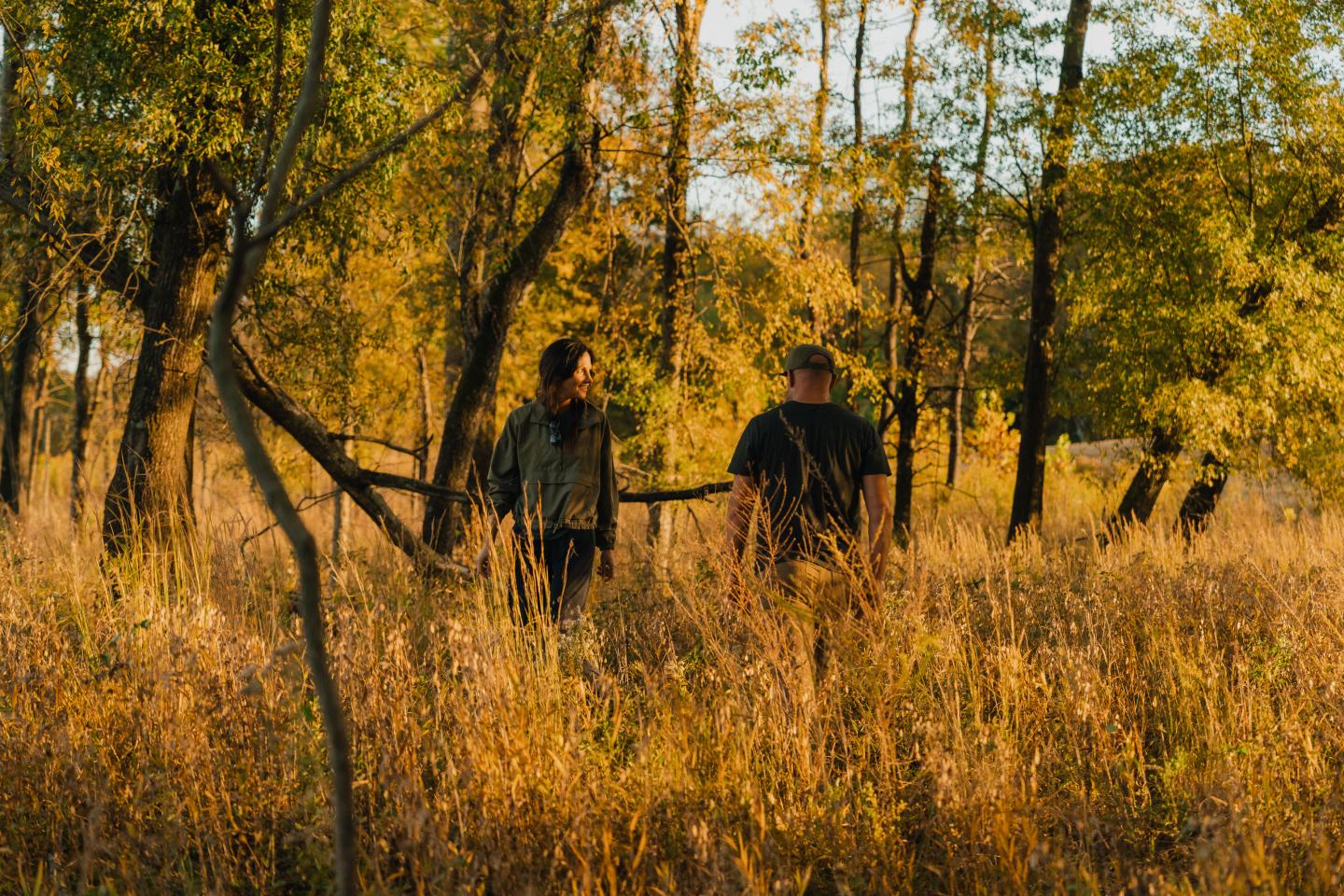 Two people walking in a sunlit autumn forest.
