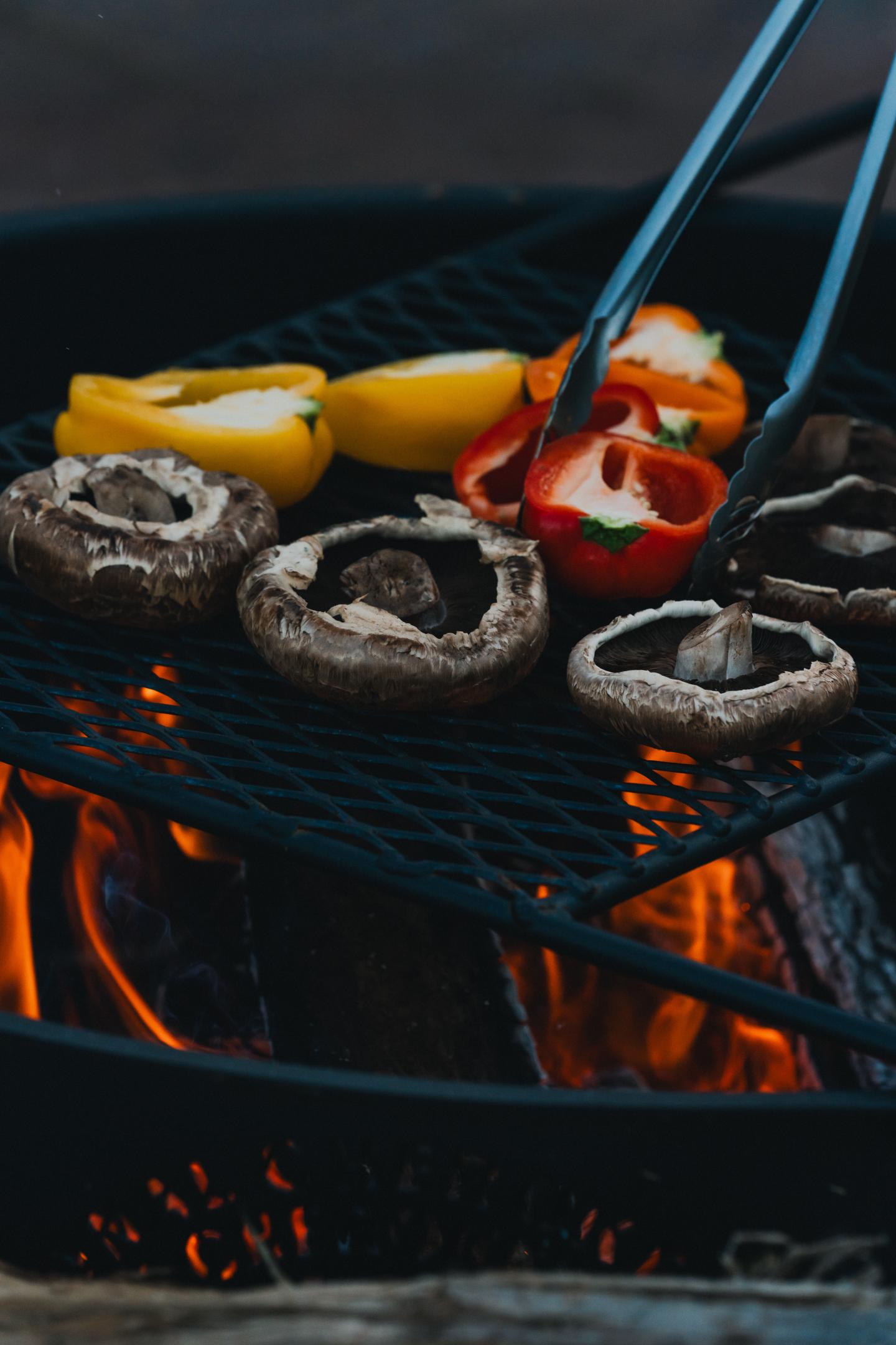 Grilling mushrooms and peppers over open flame.