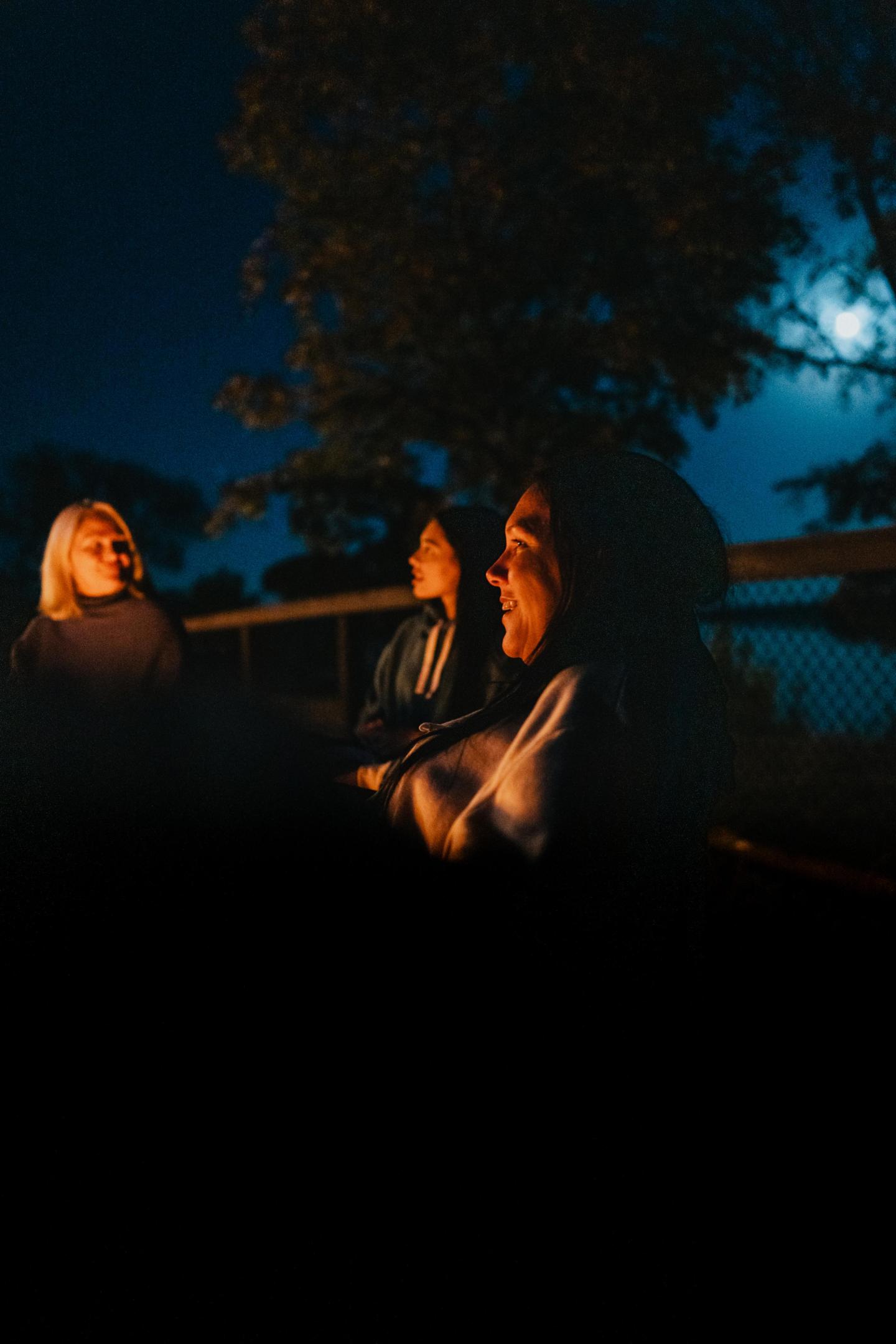 Friends laughing outdoors under moonlight.